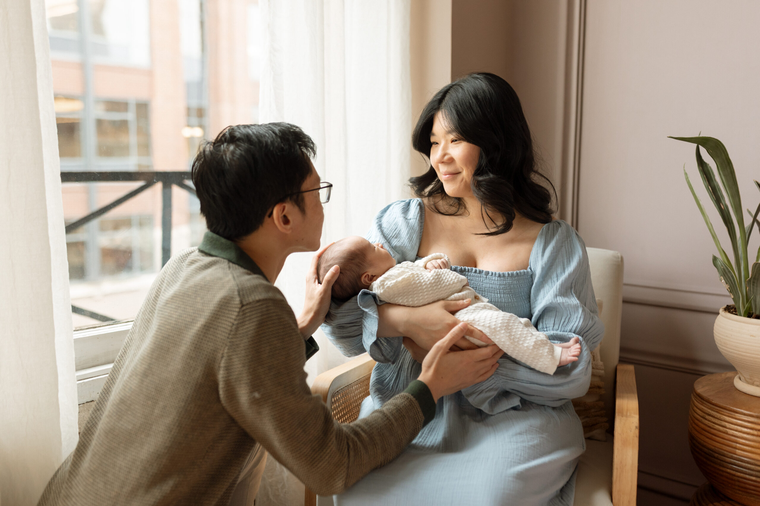 Parents gazing at their newborn near a window during an in-home Seattle newborn photographer session.