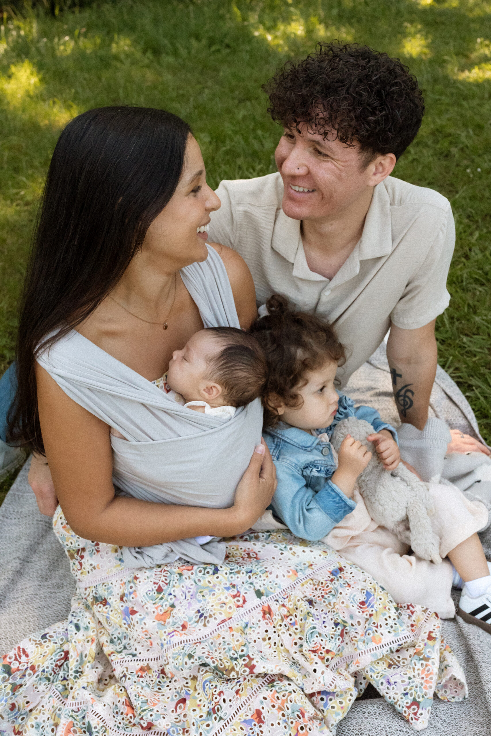 Seattle family photography session featuring parents, toddler, and newborn enjoying a quiet outdoor moment together.