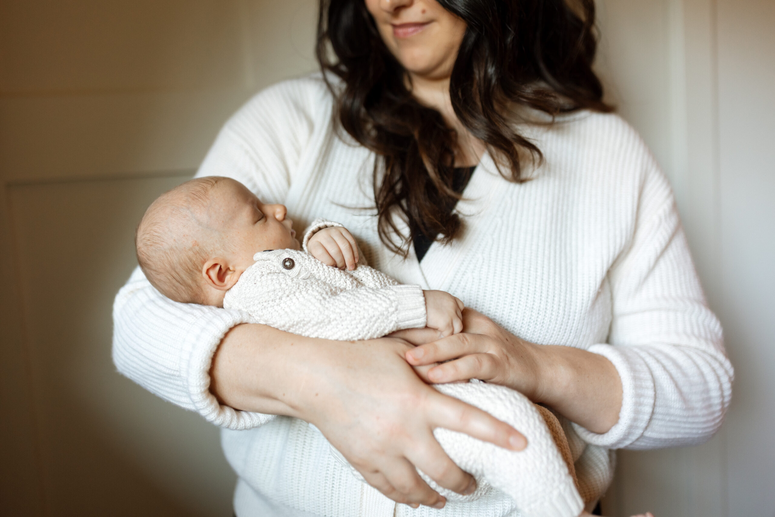 Mother holding her newborn baby in a cozy in-home session.